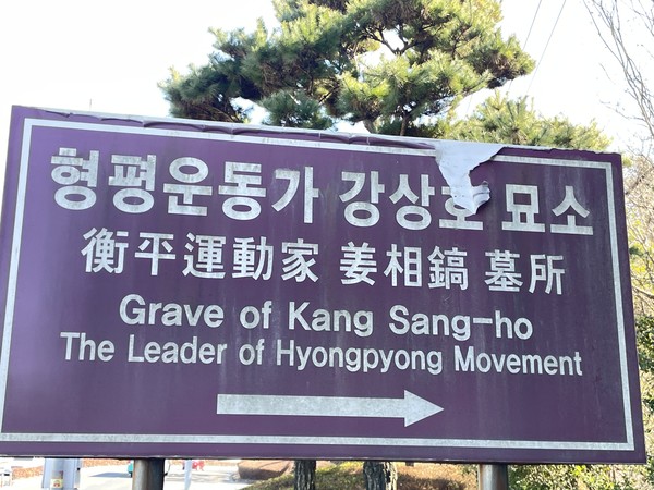 묘소 입구에는 오랜 기간 햇빛에 노출되어 빛바랜 보랏빛 표지판이 언뜻 눈에 들어온다. 표지판 모서리를 자세히 살펴보니 누군가 고의로 찢은 듯한 채로 바닥이 일부 드러나 있다.